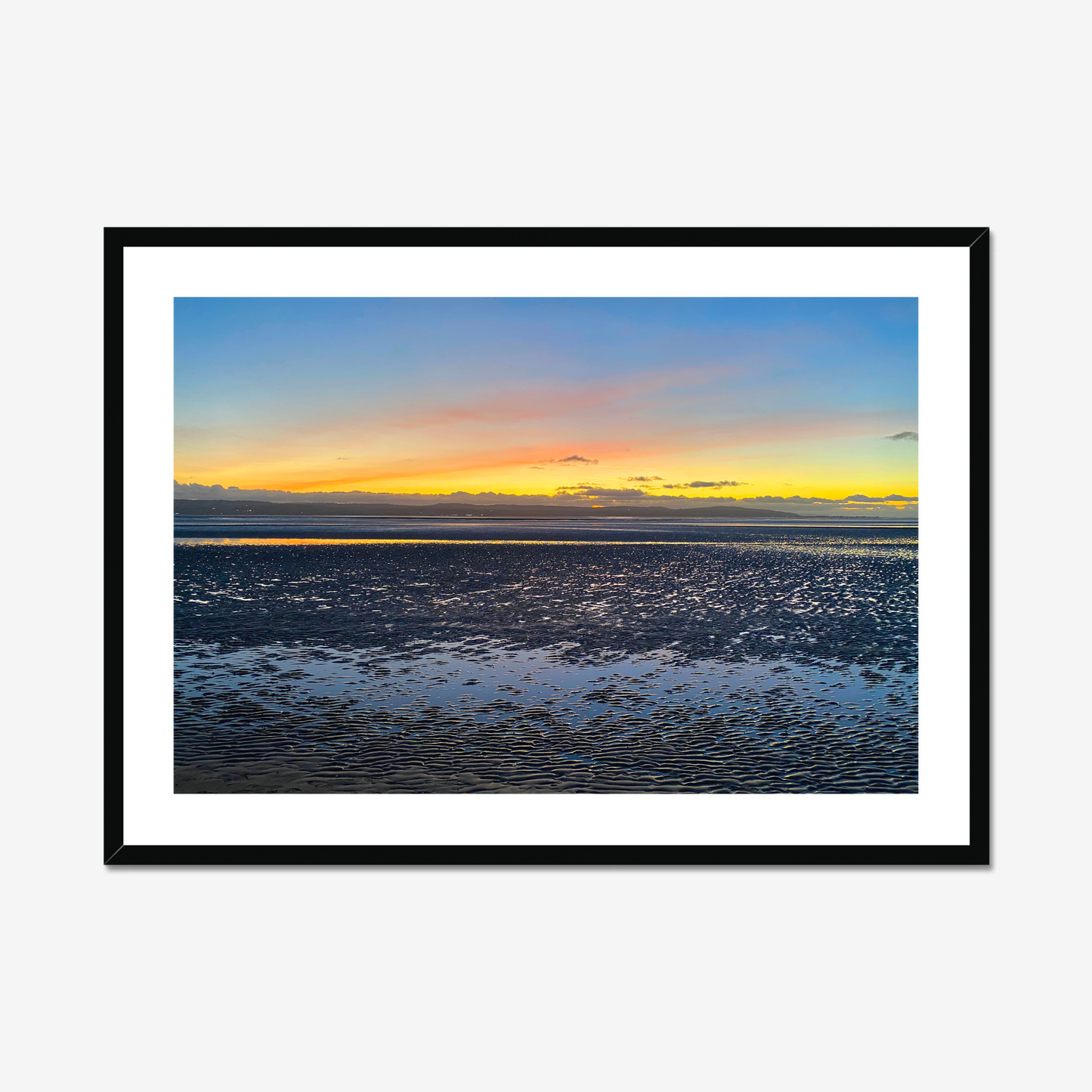 Framed photograph of a sunset over a calm body of water with a colourful sky.