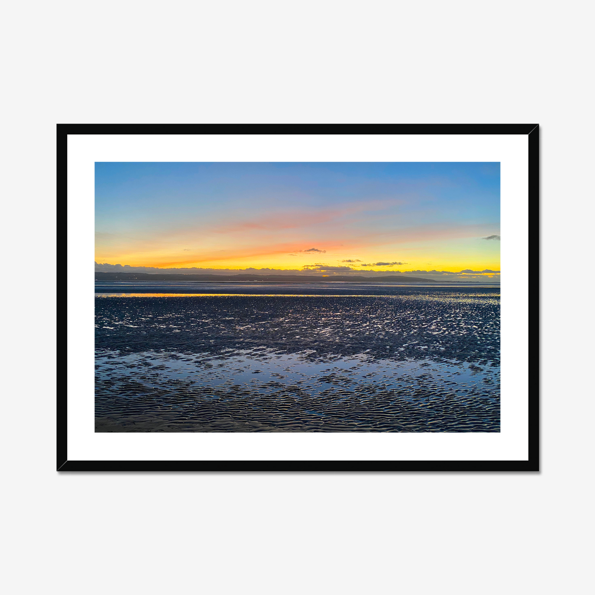 Framed photograph of a sunset over a calm body of water with a colourful sky.