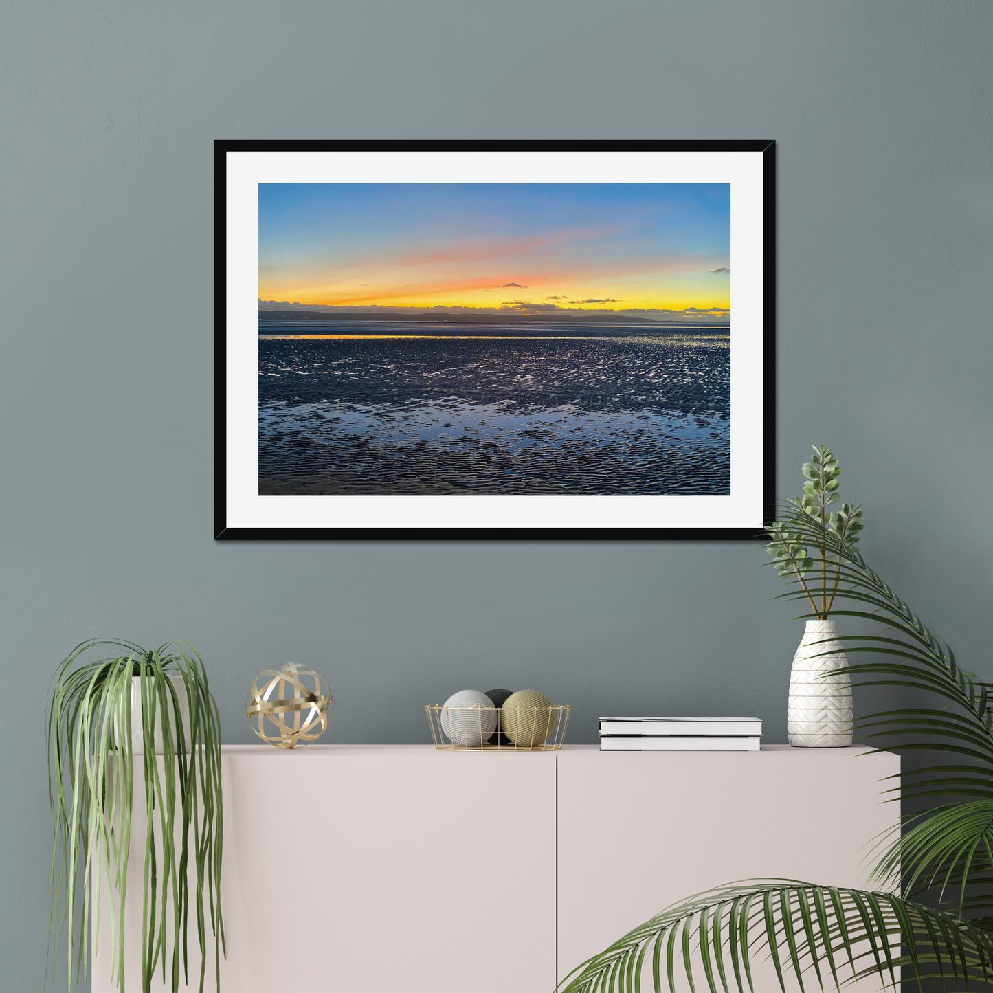 Framed photograph of a sunset over a calm body of water with a colourful sky.