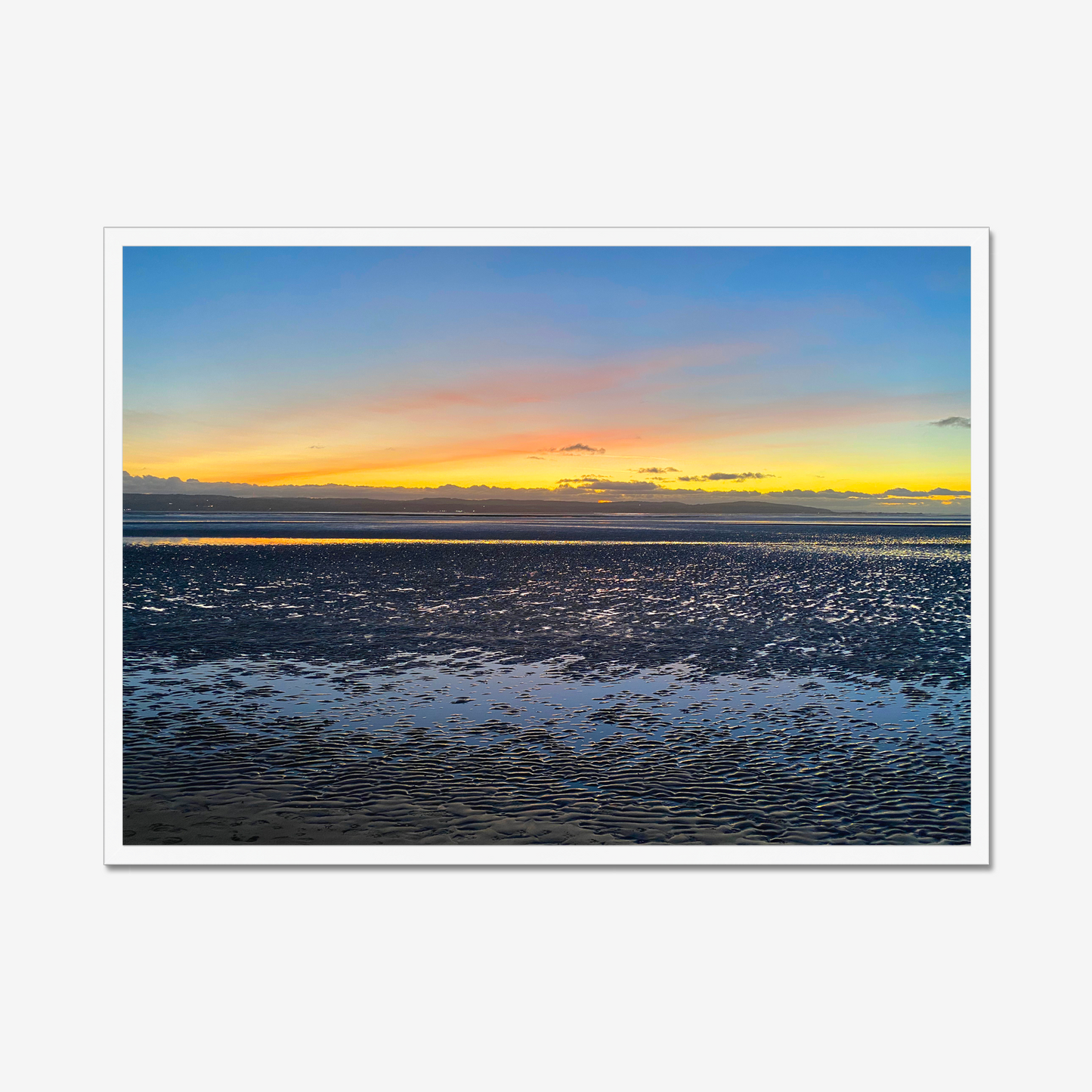 Framed photograph of a sunset over a calm body of water with a colourful sky.