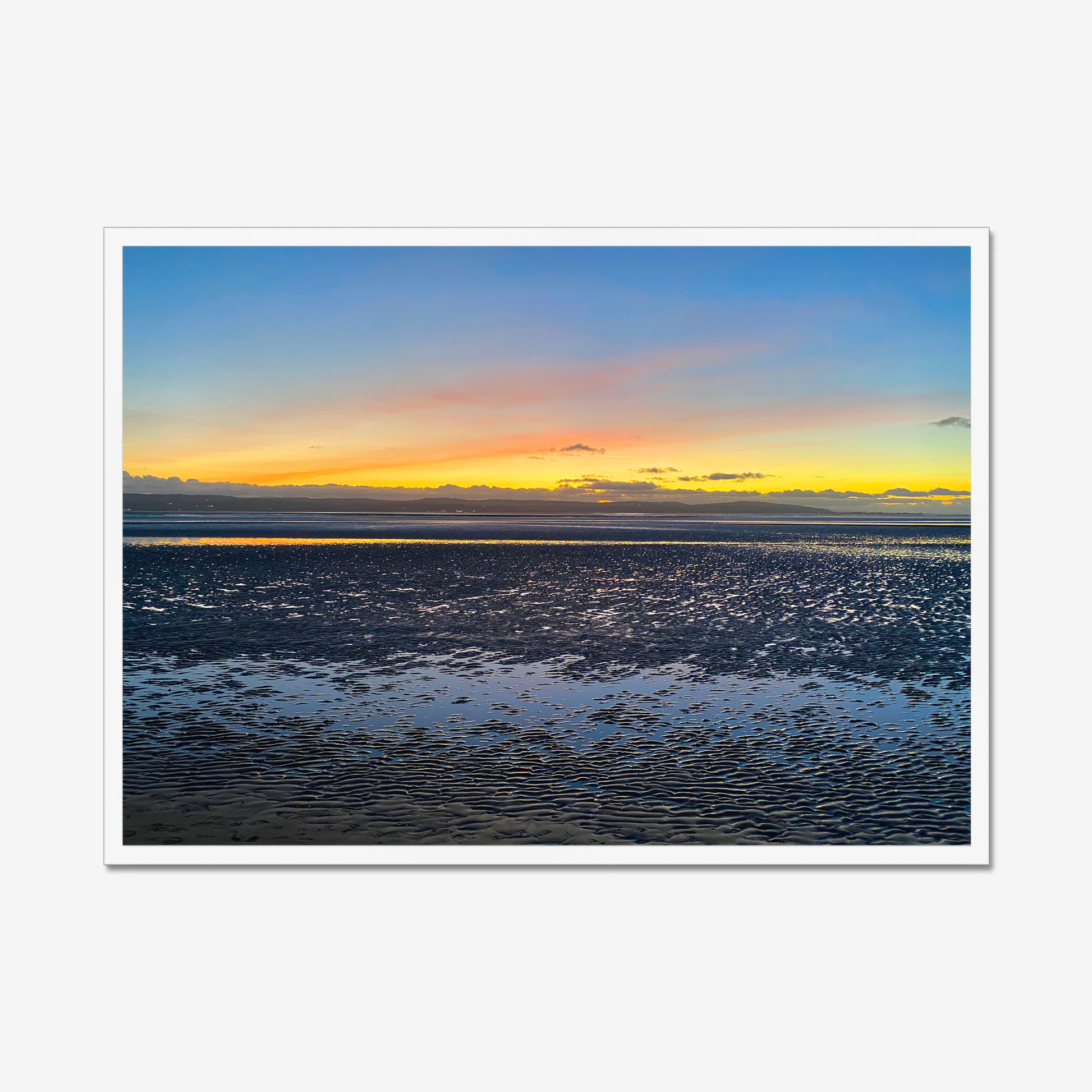 Framed photograph of a sunset over a calm body of water with a colourful sky.