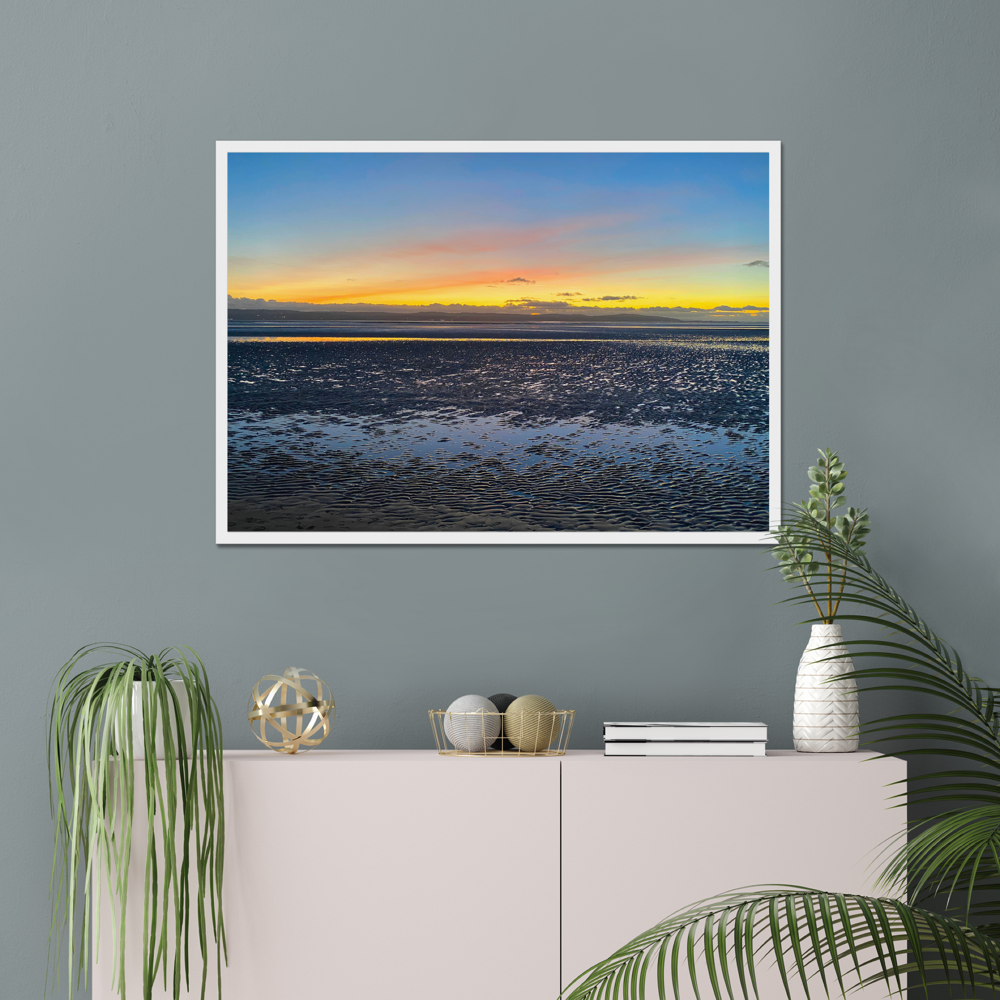 Framed photograph of a sunset over a calm body of water with a colourful sky.