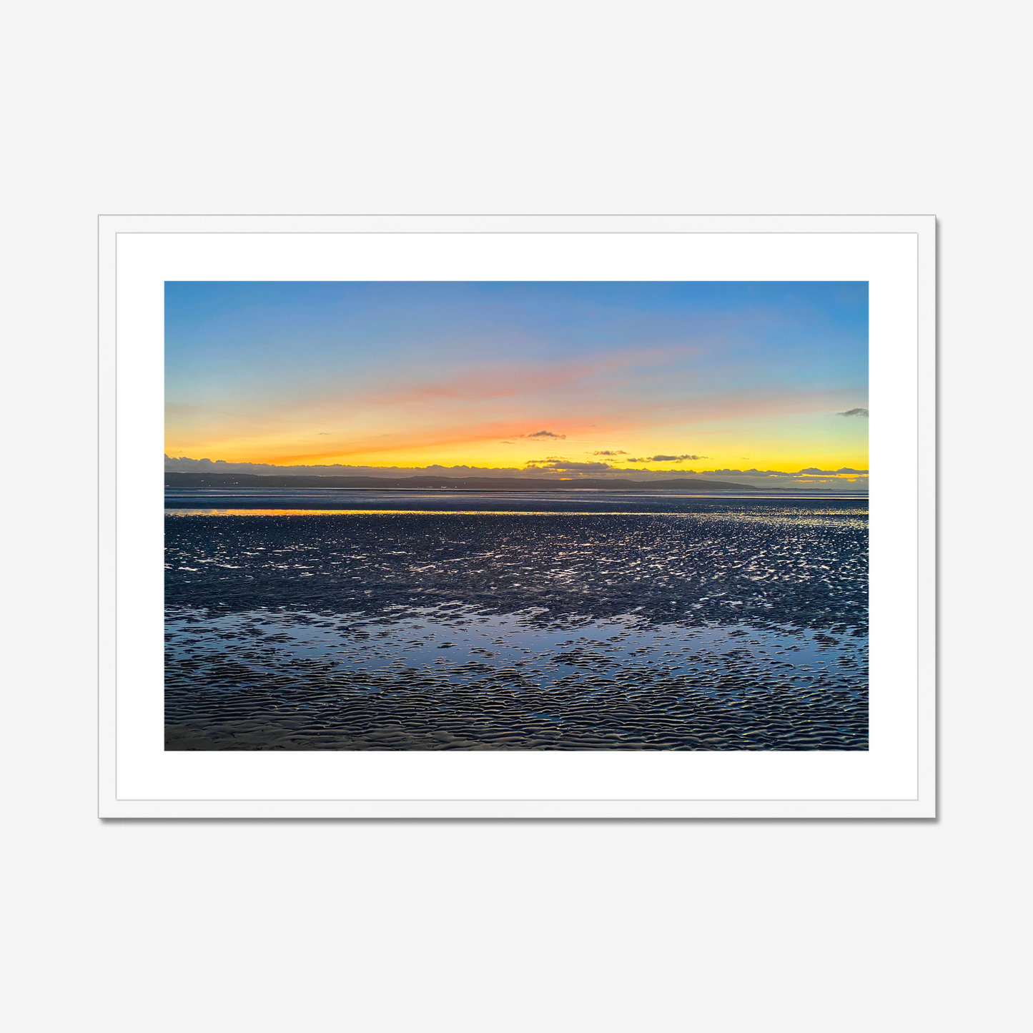 Framed photograph of a sunset over a calm body of water with a colourful sky.