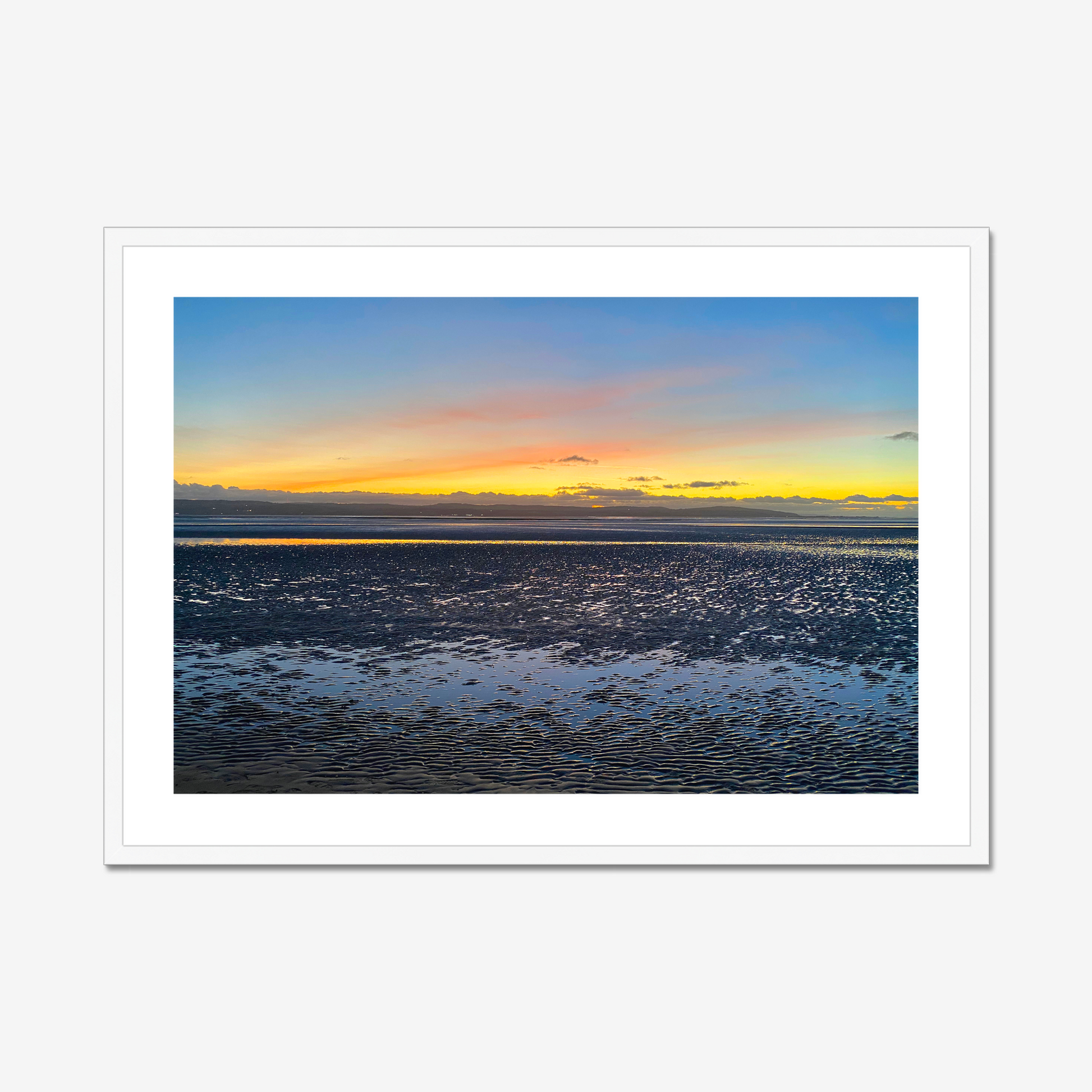 Framed photograph of a sunset over a calm body of water with a colourful sky.