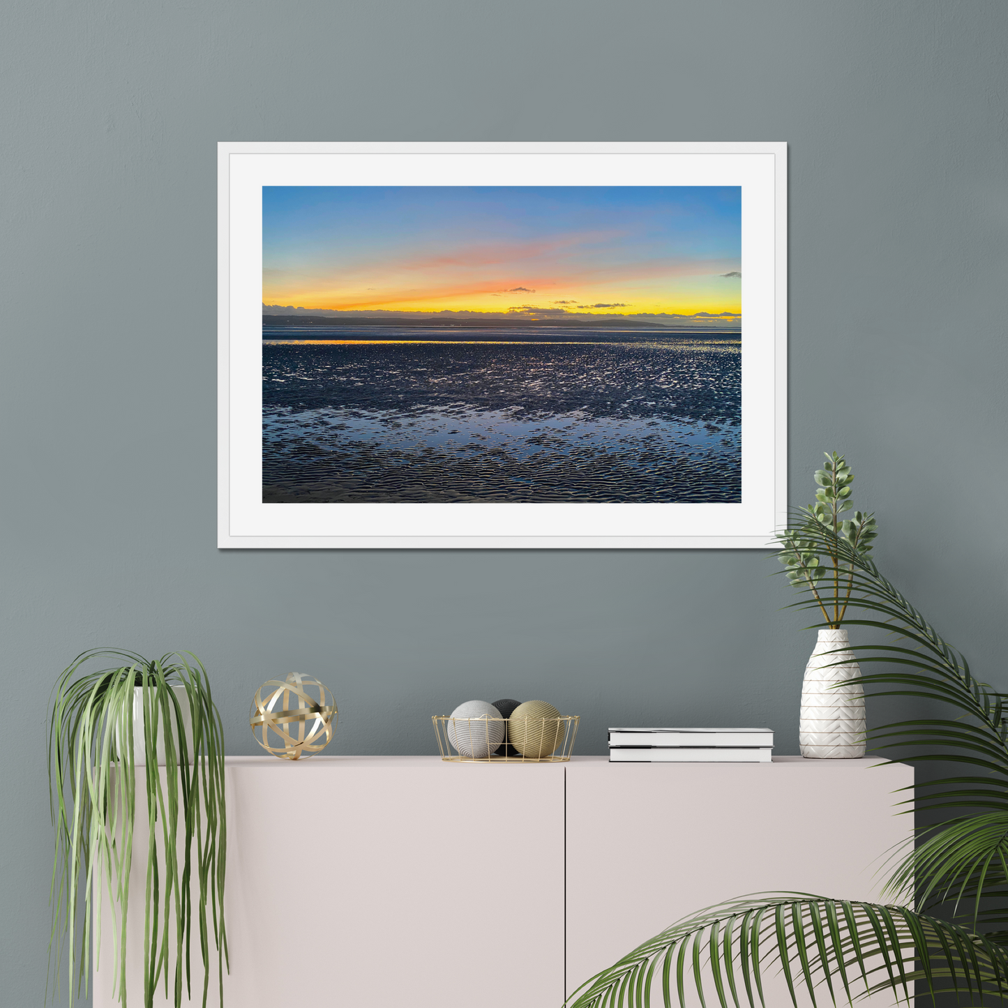 Framed photograph of a sunset over a calm body of water with a colourful sky.