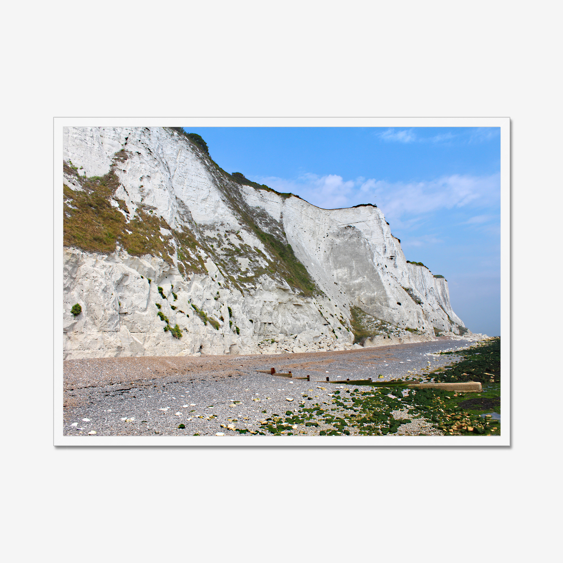 Framed photo of white cliffs with a pebbly beach and blue sky
